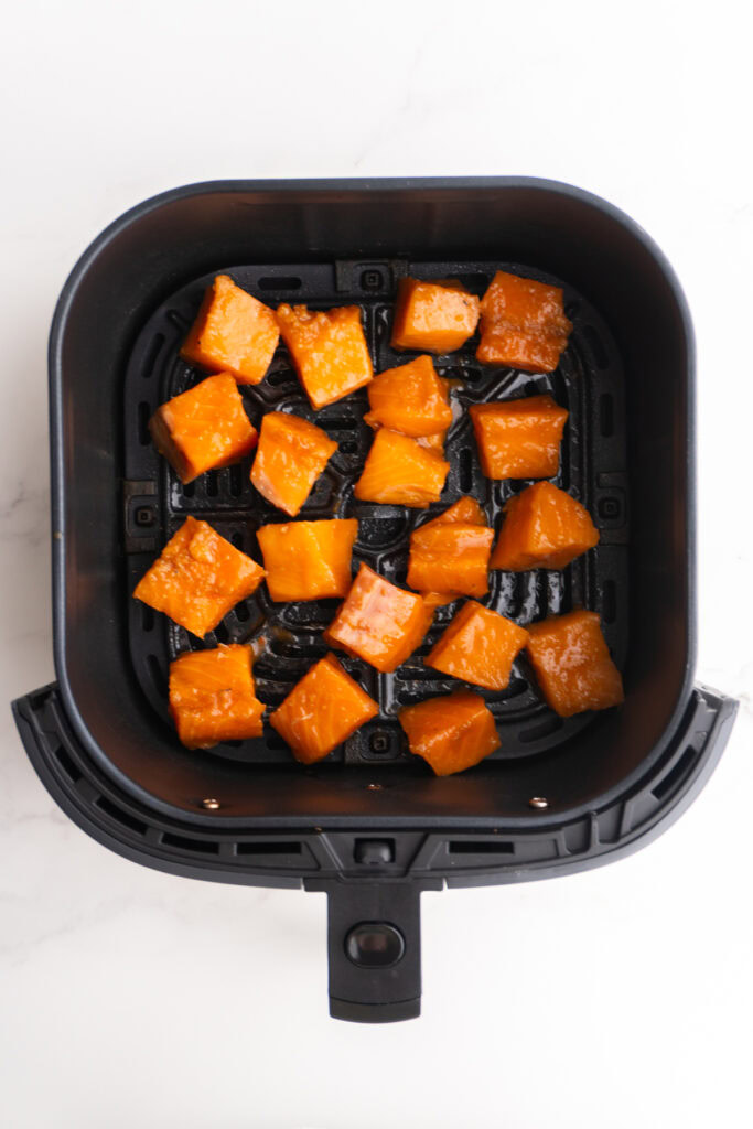 Diced and marinated salmon in the air fryer basket to cook.