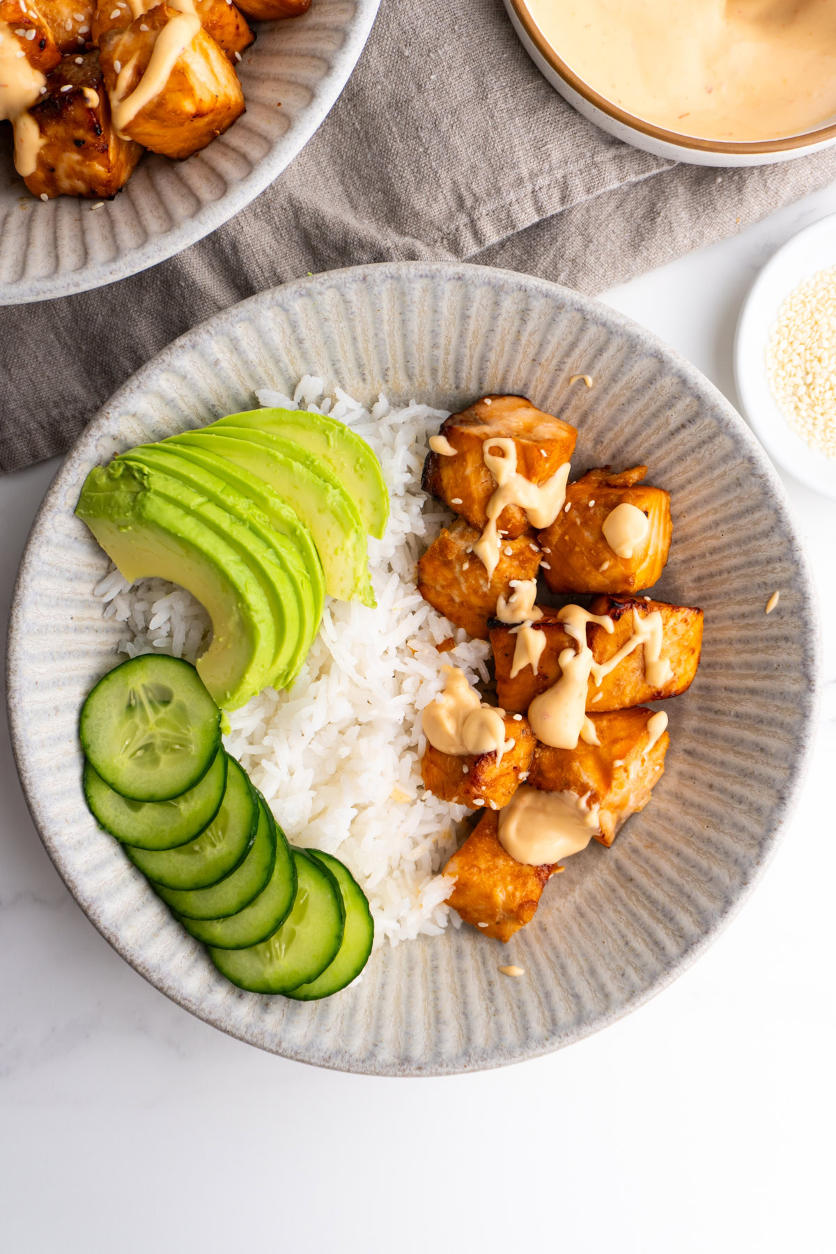 Air fryer salmon bowl garnished with avocado, cucumber and spicy mayo.