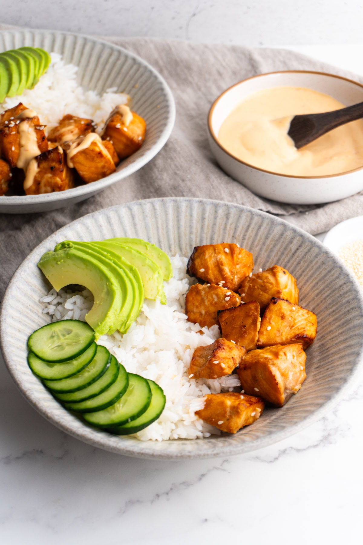 Side view of an air fryer salmon bowl with rice, avocado and cucumber.