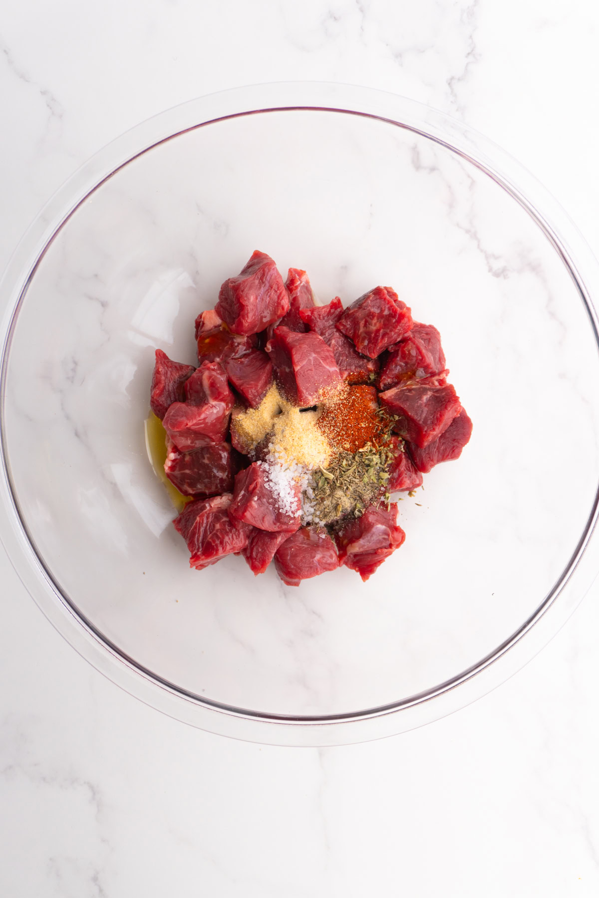 Steak with olive oil and spices in a bowl.