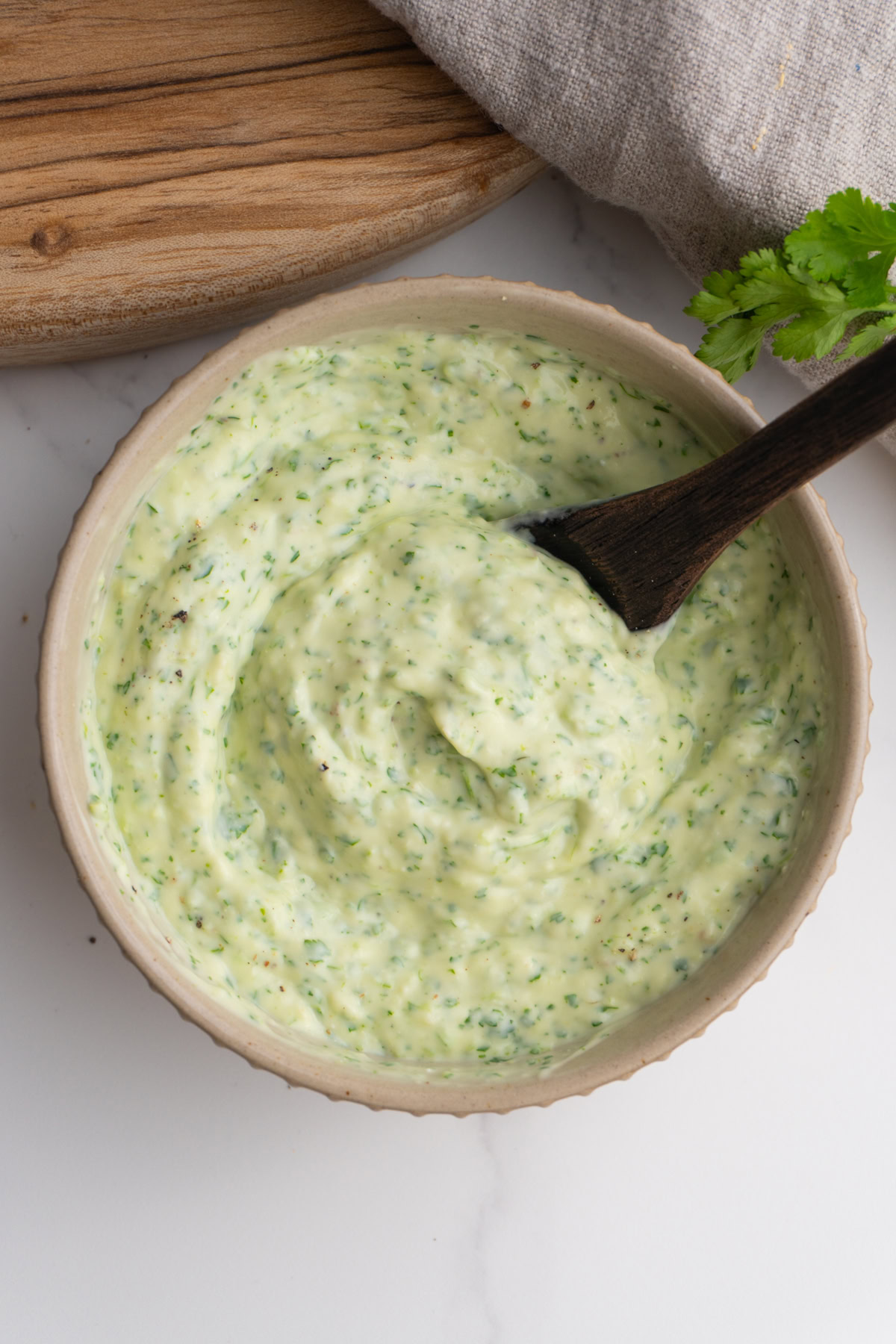 Jalapeño cilantro taco sauce in a bowl with a small wooden spoon.