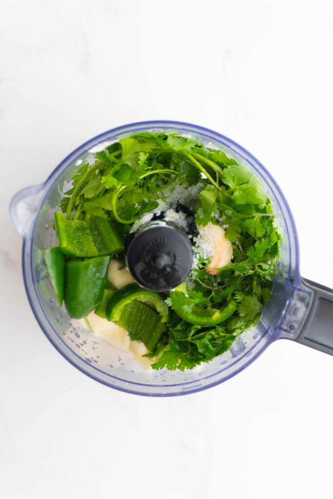 Ingredients needed for jalapeño cilantro sauce in a food processor before blending.