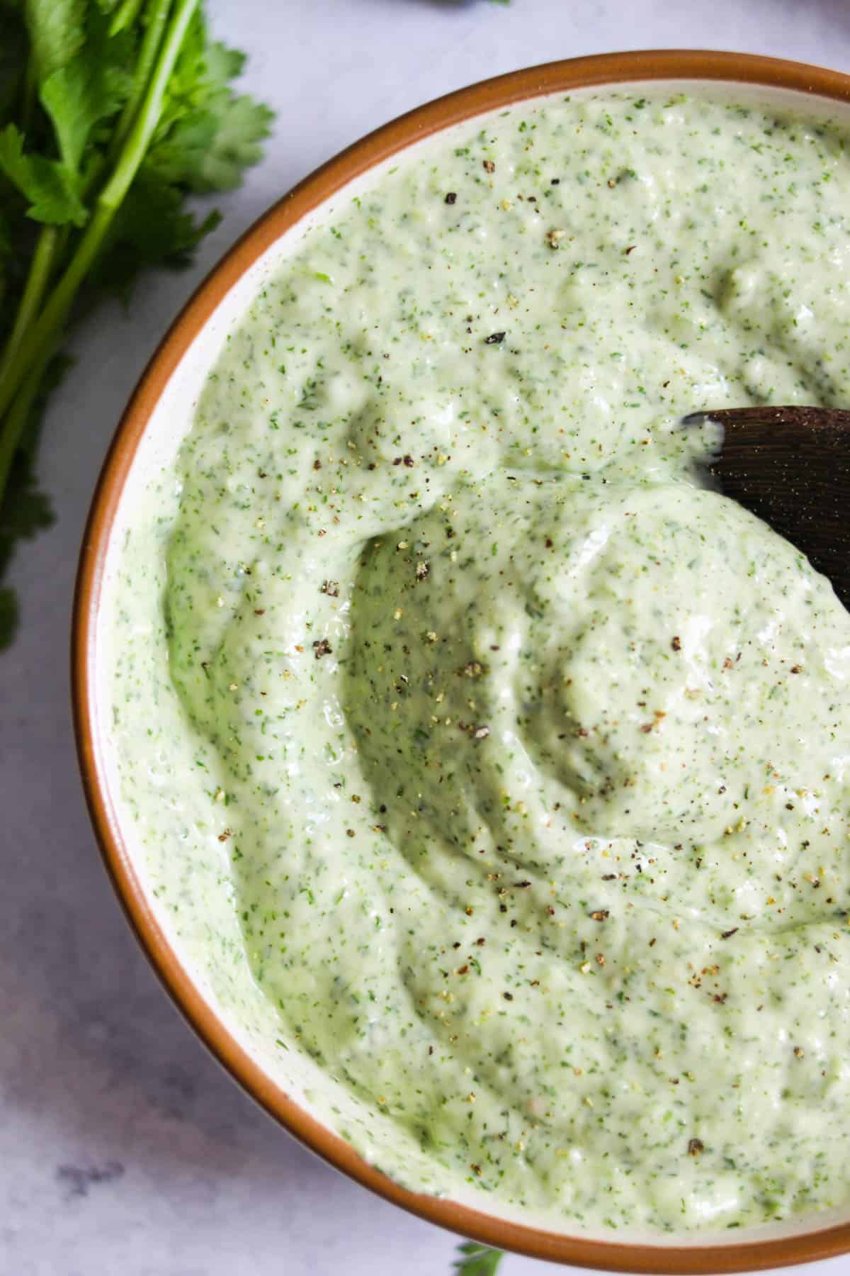 Jalapeño cilantro sauce in a bowl with black pepper on top.