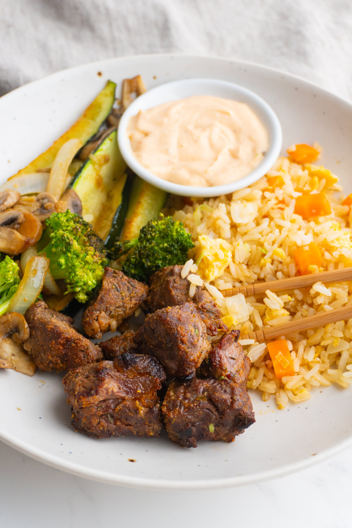 Side view of hibachi steak bowl with yum yum sauce on the side.