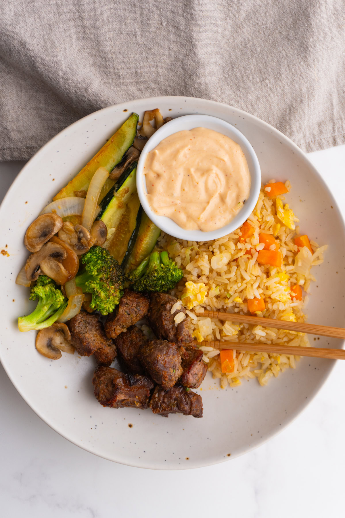 Overhead shot of hibachi steak bowls in a bowl with yum yum sauce on the side.