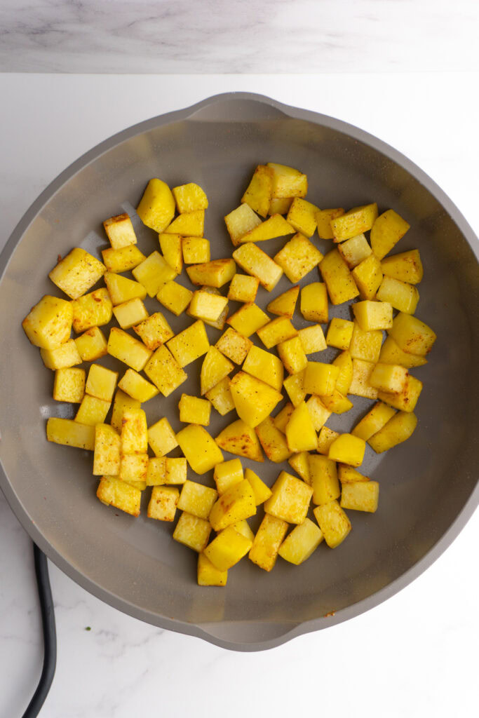 Seared potato cubes in a skillet.
