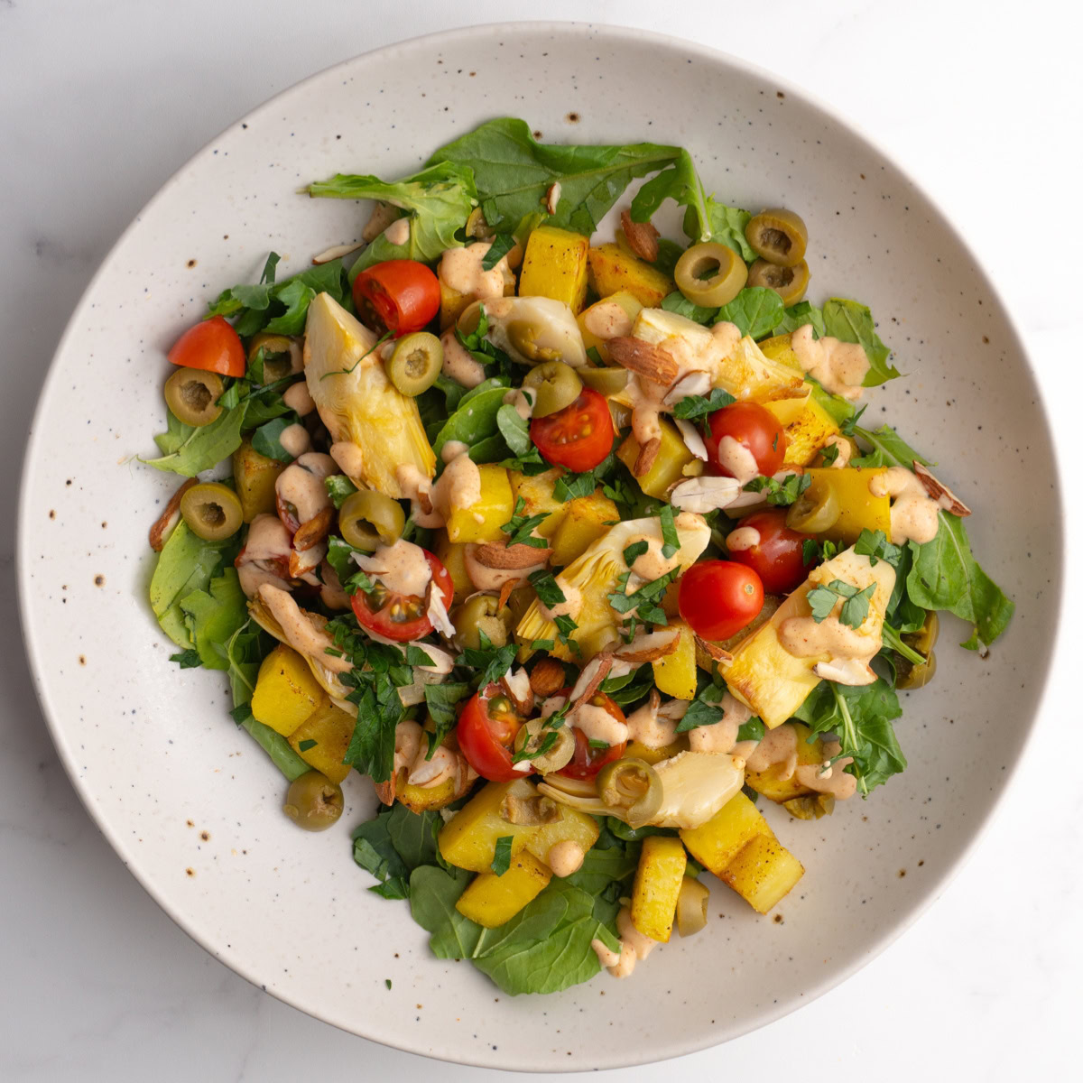 Patatas bravas salad bowl in a speckled white bowl.