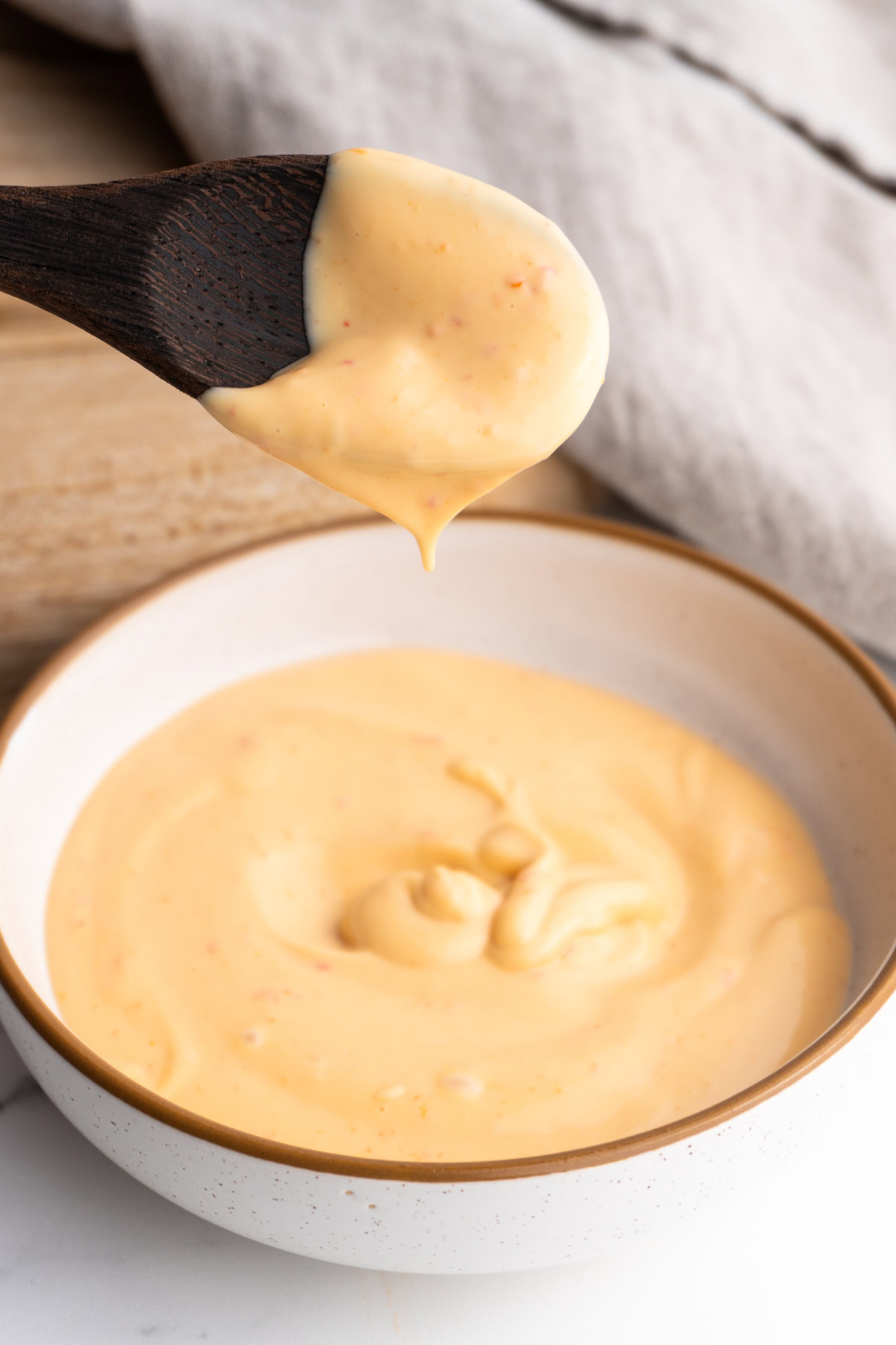 Sriracha spicy mayo with a spoon hovering above it after being dipped in.