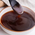 Teriyaki sauce in a bowl with a spoon scooping some up.