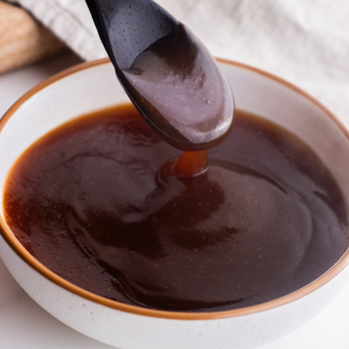 Teriyaki sauce in a bowl with a spoon scooping some up.