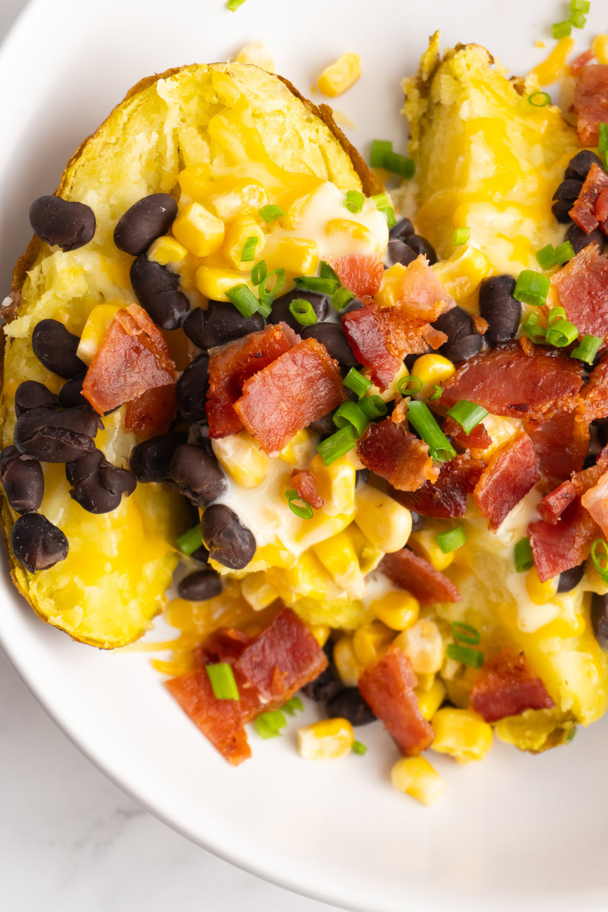 Close up of a loaded baked potato with toppings like cheese, beans and bacon.