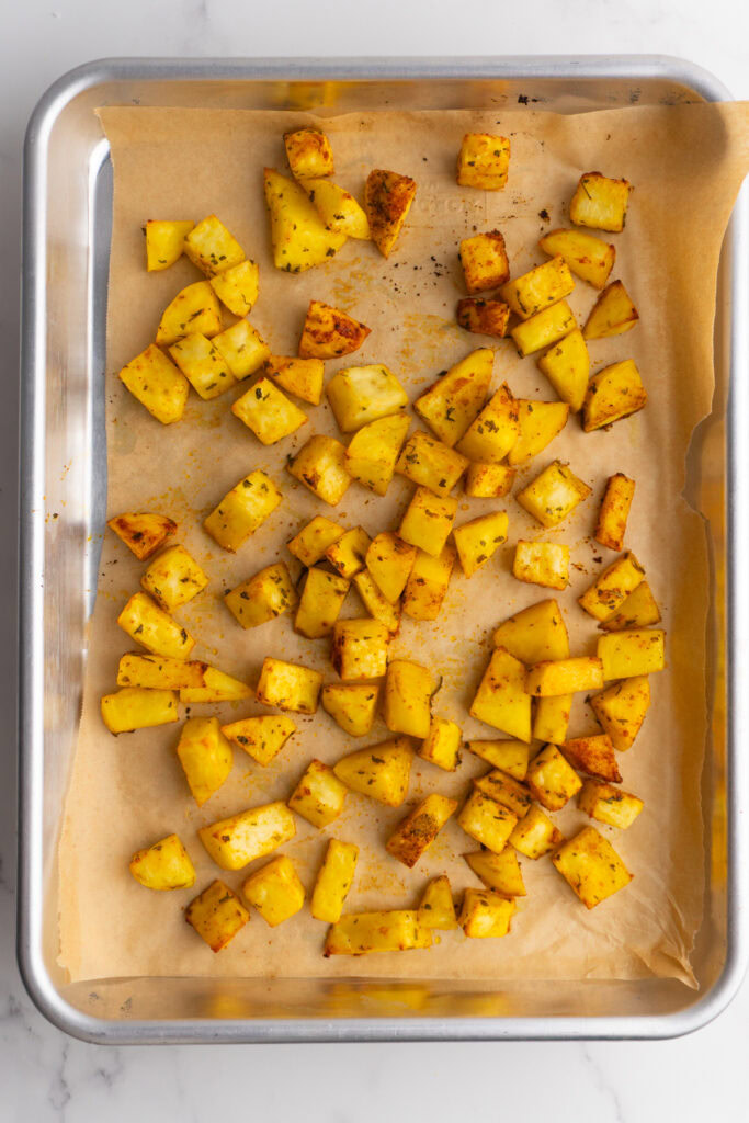 Roasted potatoes on a sheet pan with parchment paper.