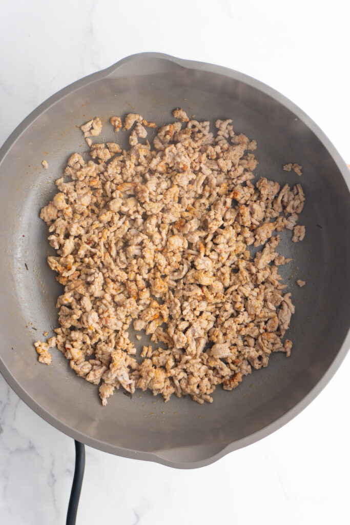 Ground pork searing in a pan.