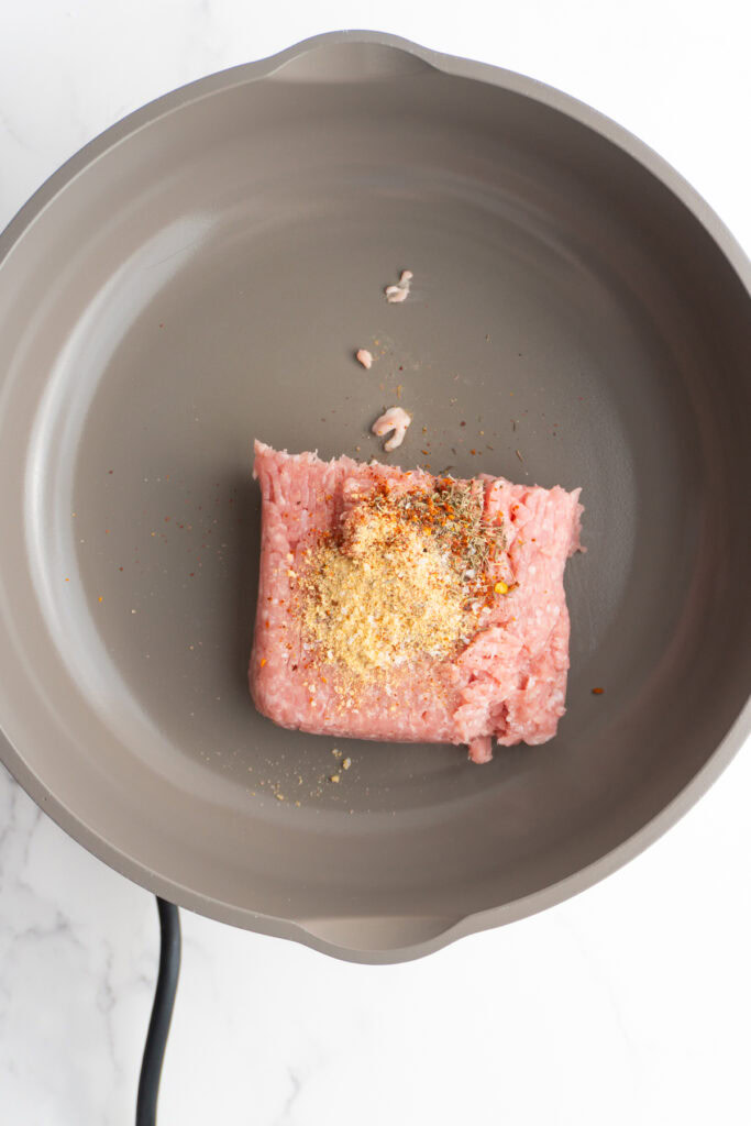 Ground pork with spices on top in a skillet.