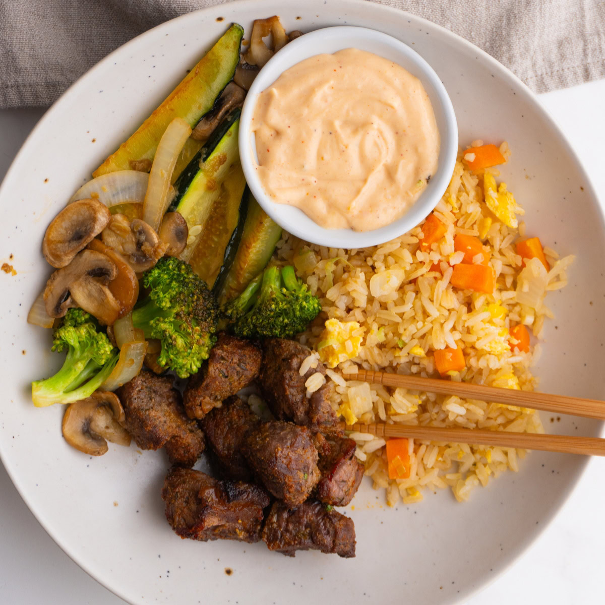 Overhead shot of a hibachi bowl with steak and yum yum sauce.