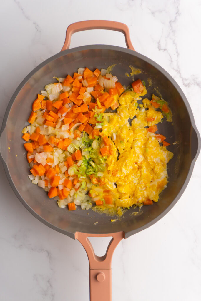 Green onions added to the skillet of scrambled eggs and veggies.