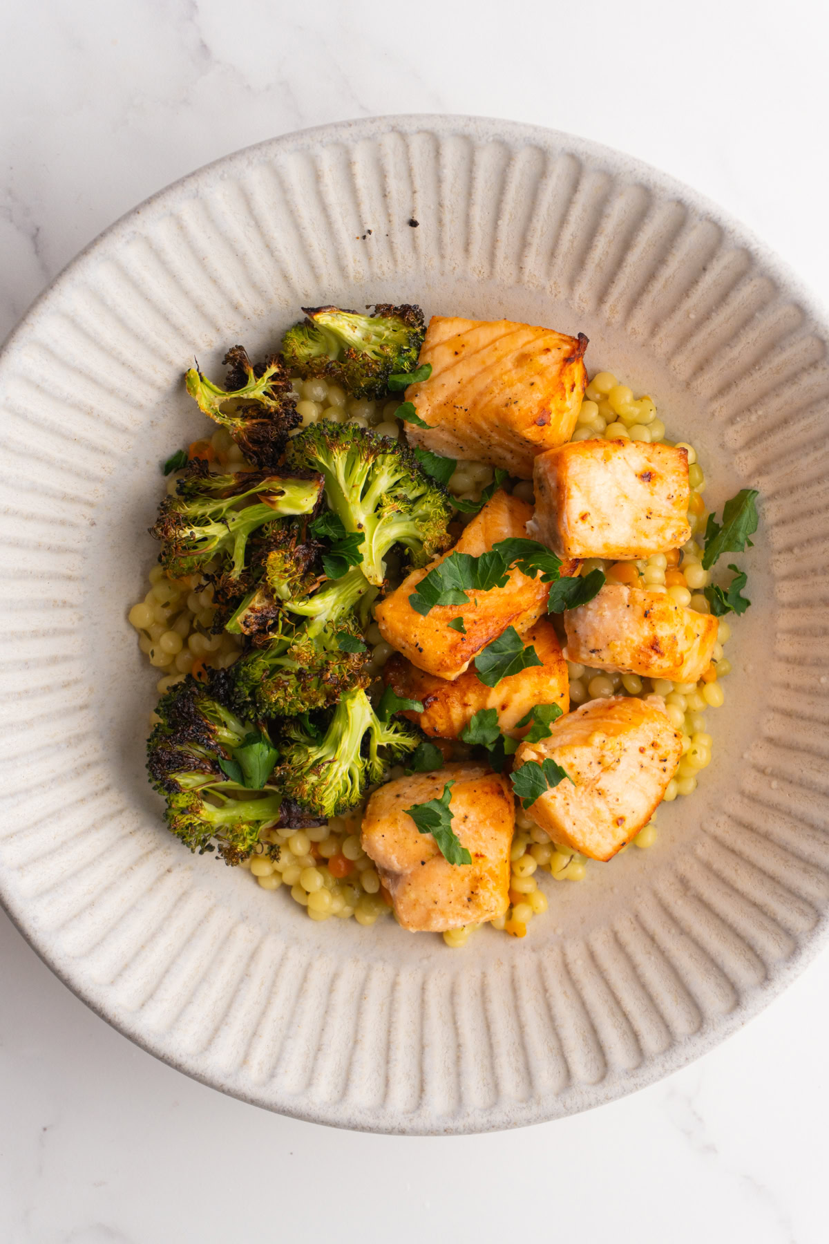 Overhead shot of salmon couscous bowl garnished with parsley.