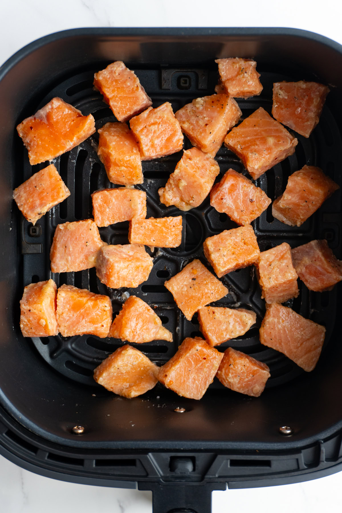 Seasoned salmon in the air fryer basket before cooking.