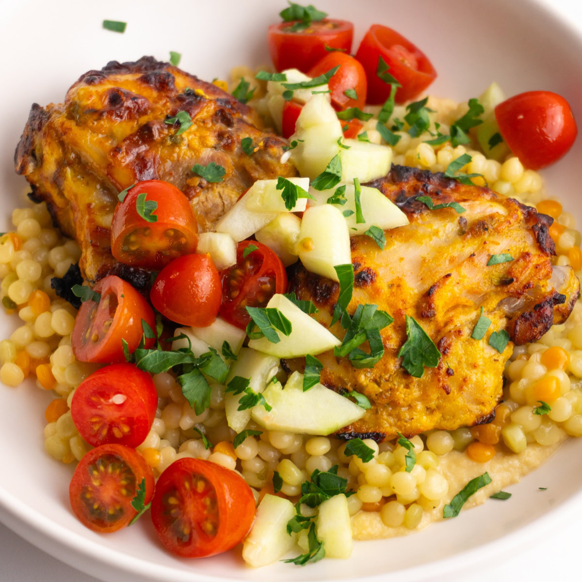 Shawarma hummus couscous bowls topped with tomato and cucumber salad.
