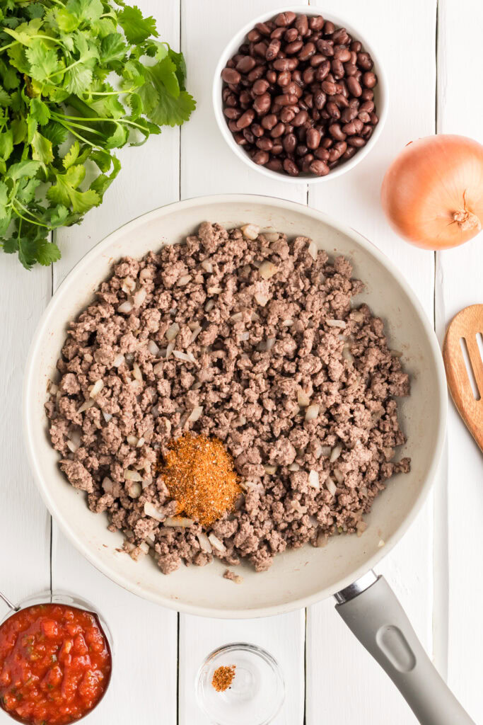 Ground beef with onion and taco seasoning in a skillet.