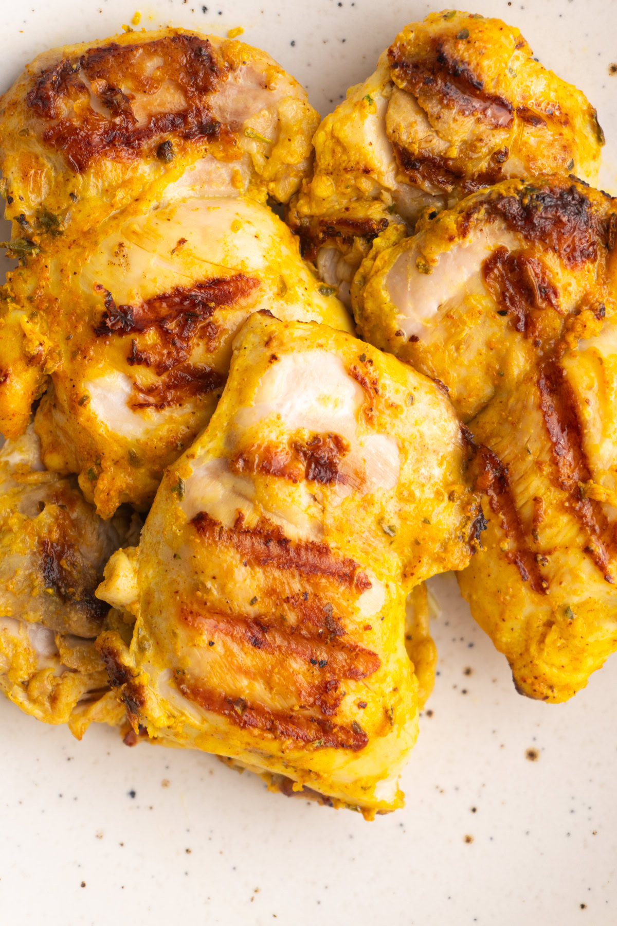 Overhead shot of chicken thighs stacked on top of each other in a bowl.