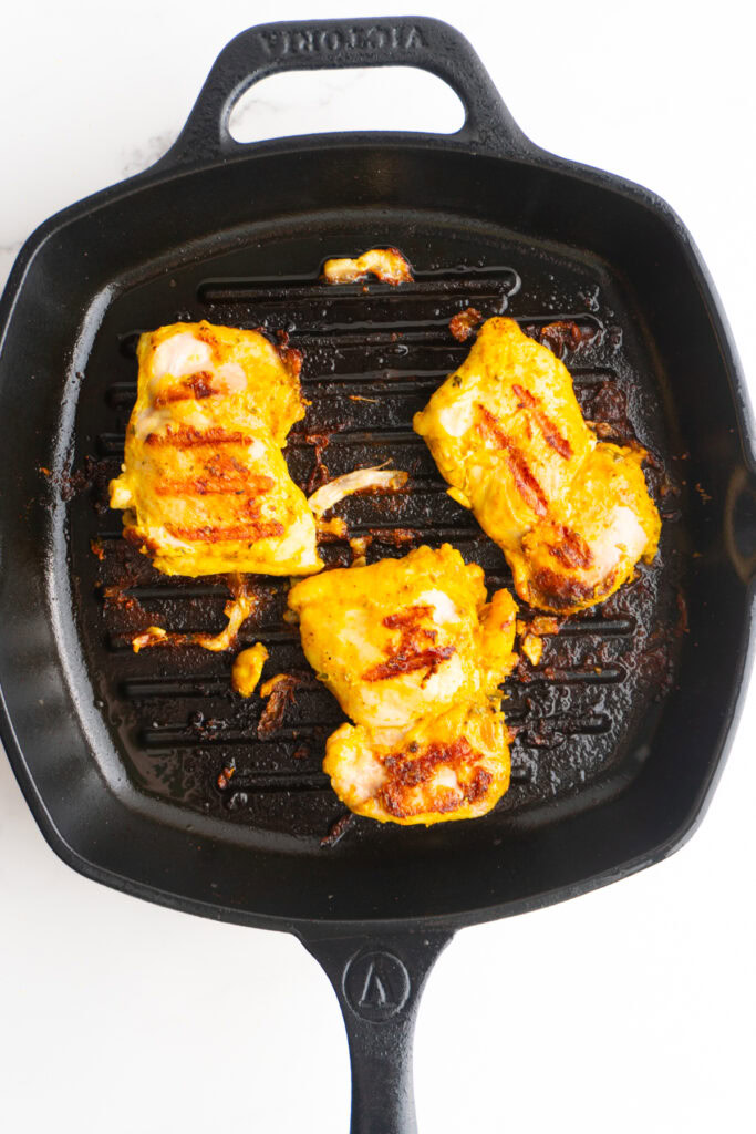 Chicken thighs flipped in a skillet.