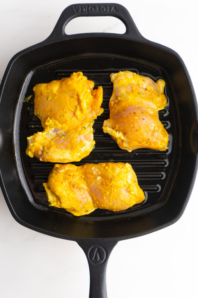 Chicken marinated in chicken shawarma marinade on a skillet.