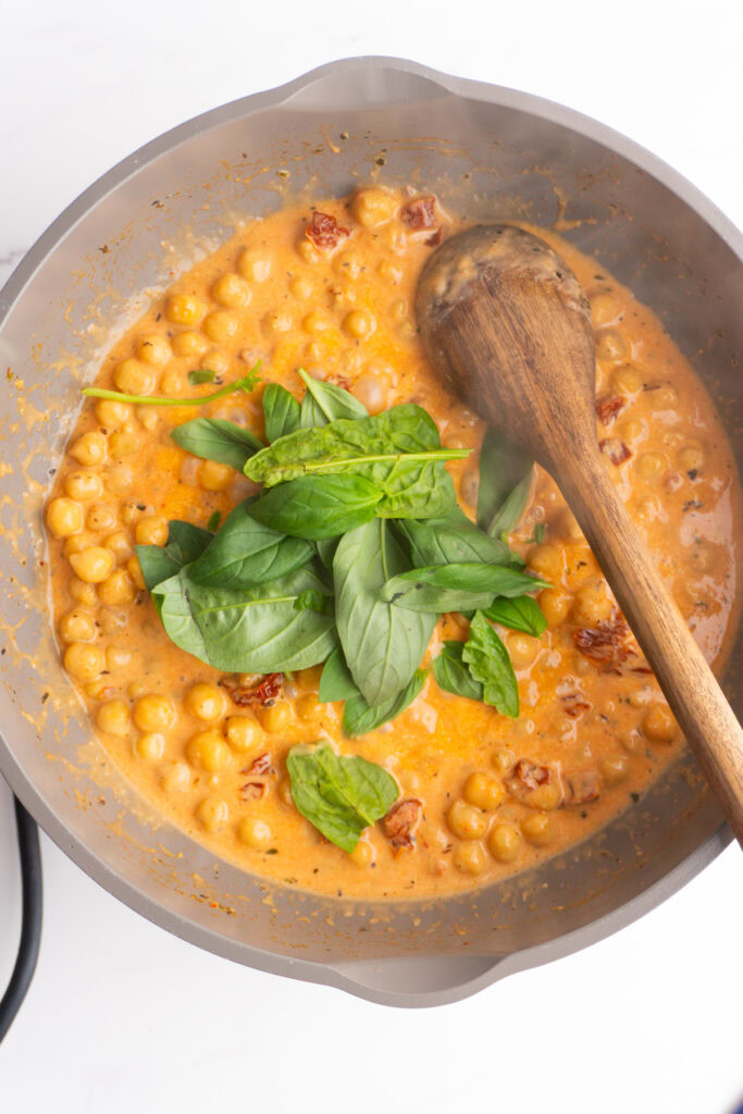 Stirring in the spinach to the marry me chickpeas.