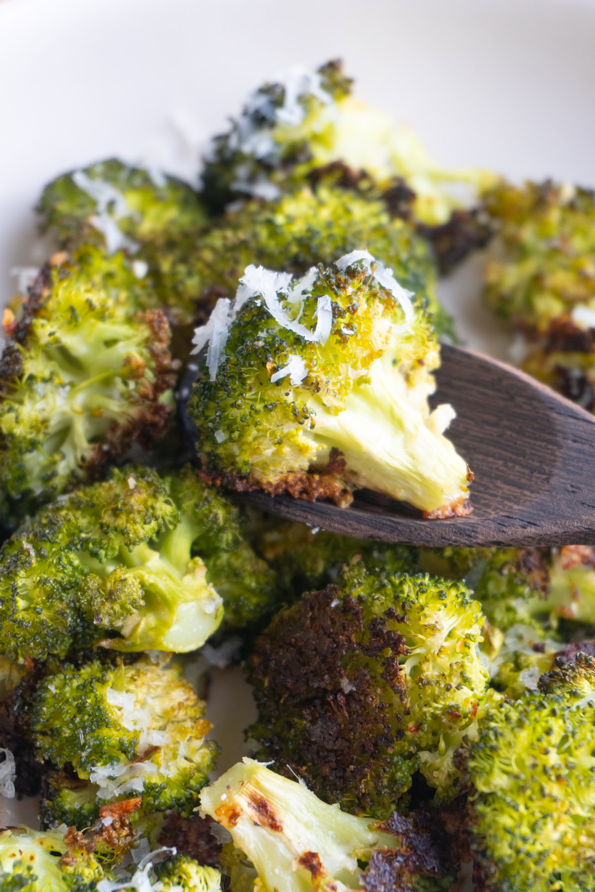 Parmesan broccoli in a bowl with one being scooped by a spoon.