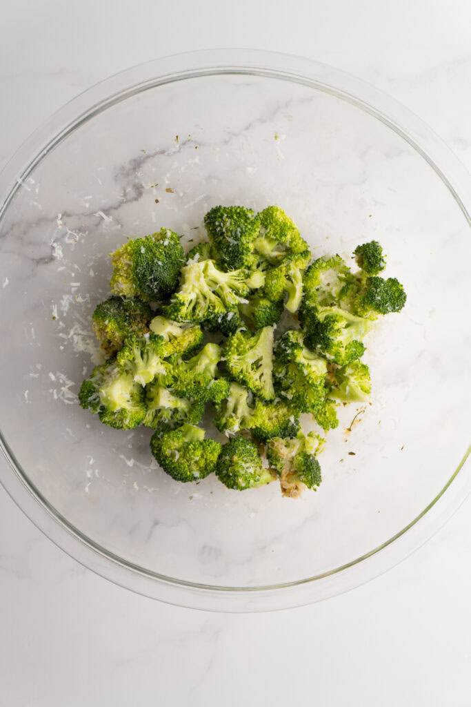 Seasoned broccoli florets in a mixing bowl.