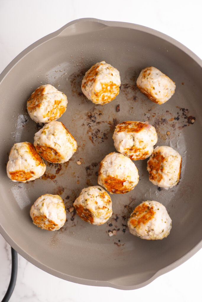 Seared Greek turkey meatballs in a skillet.