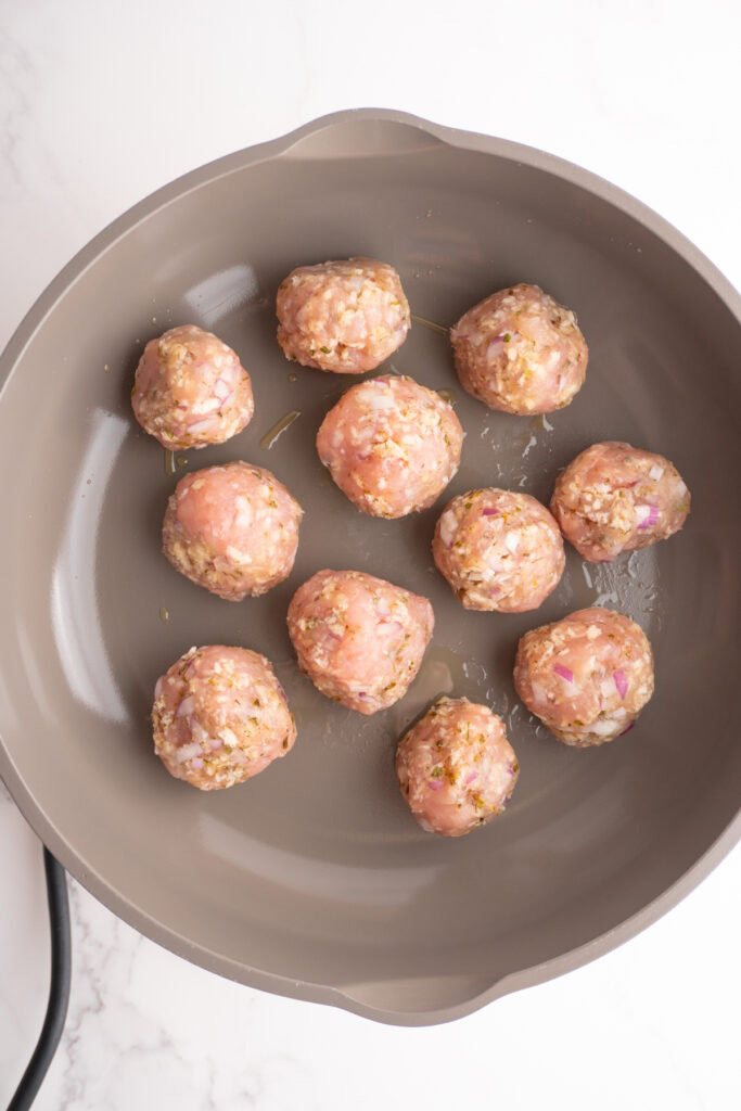 Greek turkey meatballs in a skillet to be cooked.