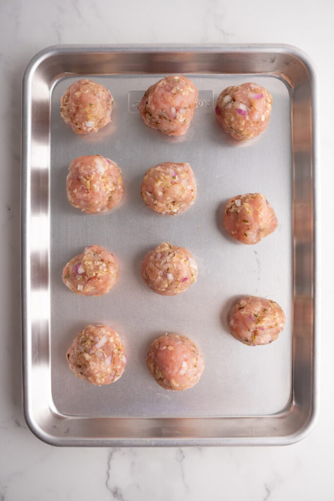 Assembled turkey meatballs on a sheet pan.