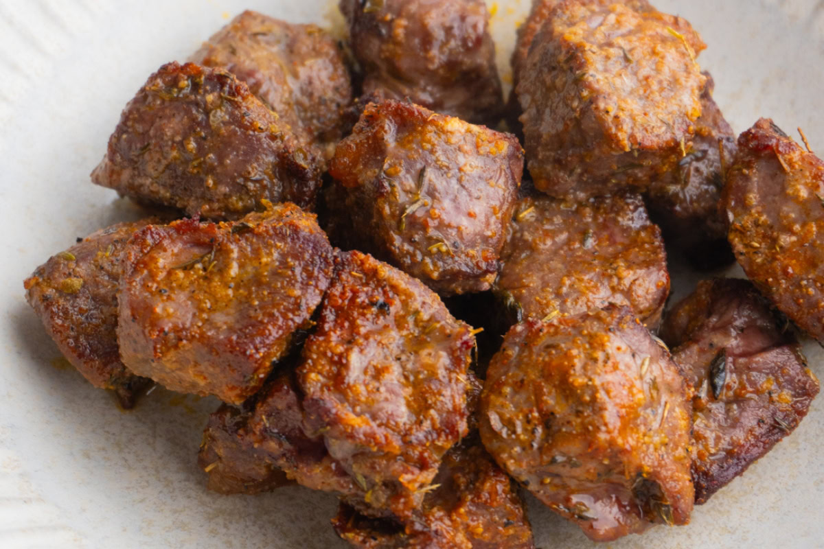 Close up of air fryer steak bites piled together in a bowl.