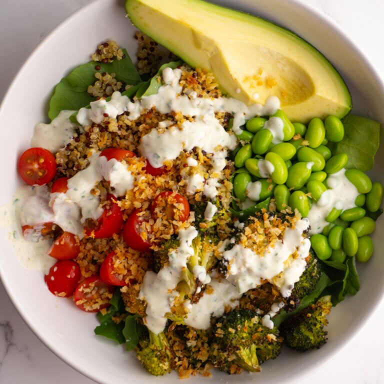 Green goddess bowl with veggies, quinoa, toasted breadcrumbs, and creamy sauce on top.