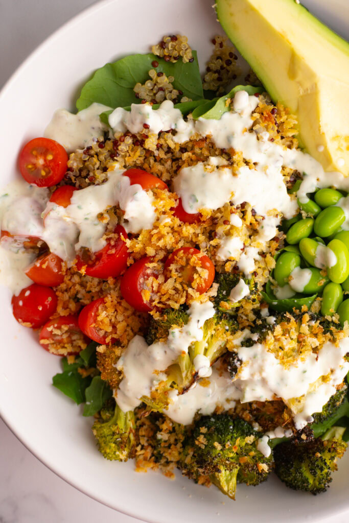 Overhead shot of green goddess bowl with breadcrumbs and a sauce drizzled on top.