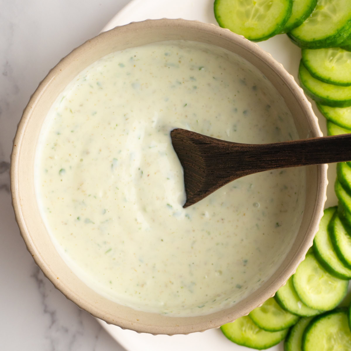 Bowl served with green goddess dip with a small wooden spoon.