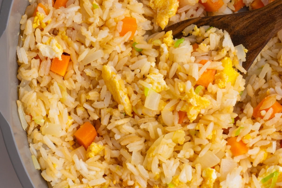 Hibachi fried rice in a skillet with a wooden spoon.