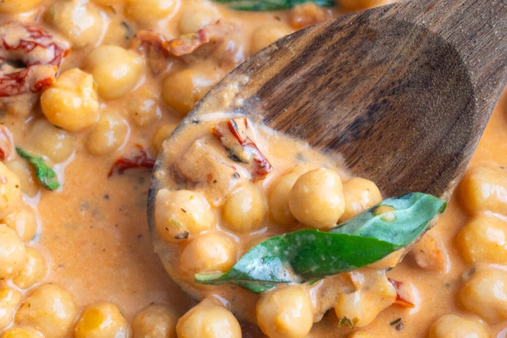 Close up of marry me chickpeas on a wooden spoon.