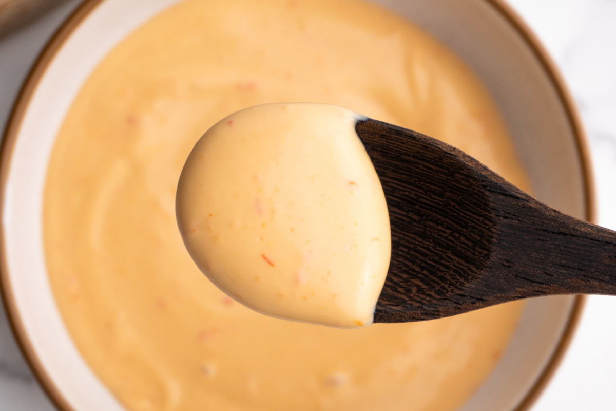 Close up of sriracha mayo on a wooden spoon.