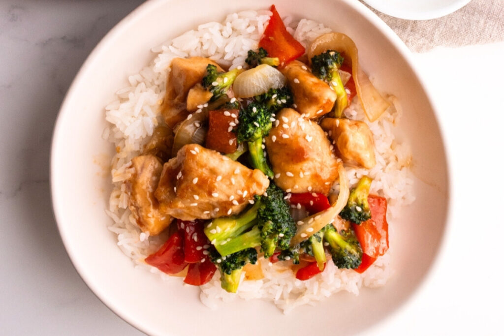 Close up of chicken teriyaki and rice bowl garnished with sesame seeds on top.