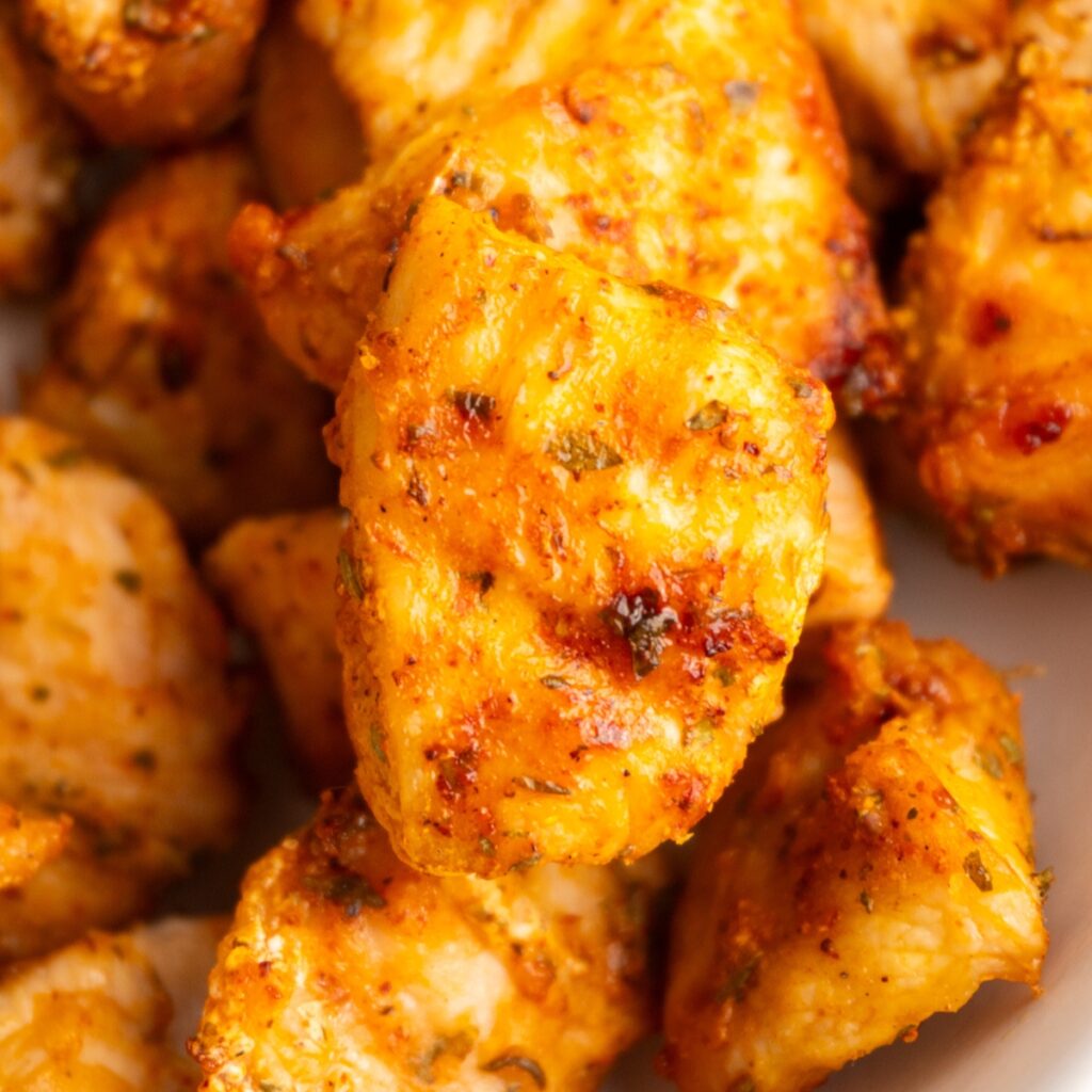Close up of an air fried chicken bite on top of others in a bowl.