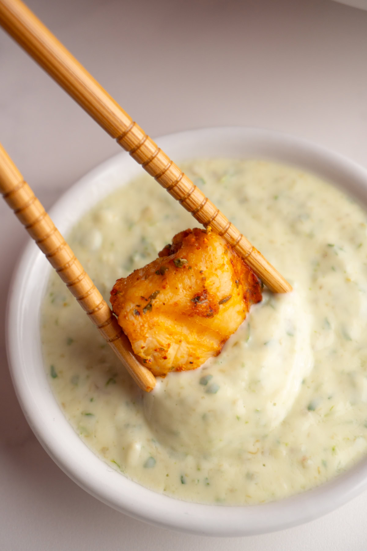 Air fryer chicken bite being dipped into green goddess dip.