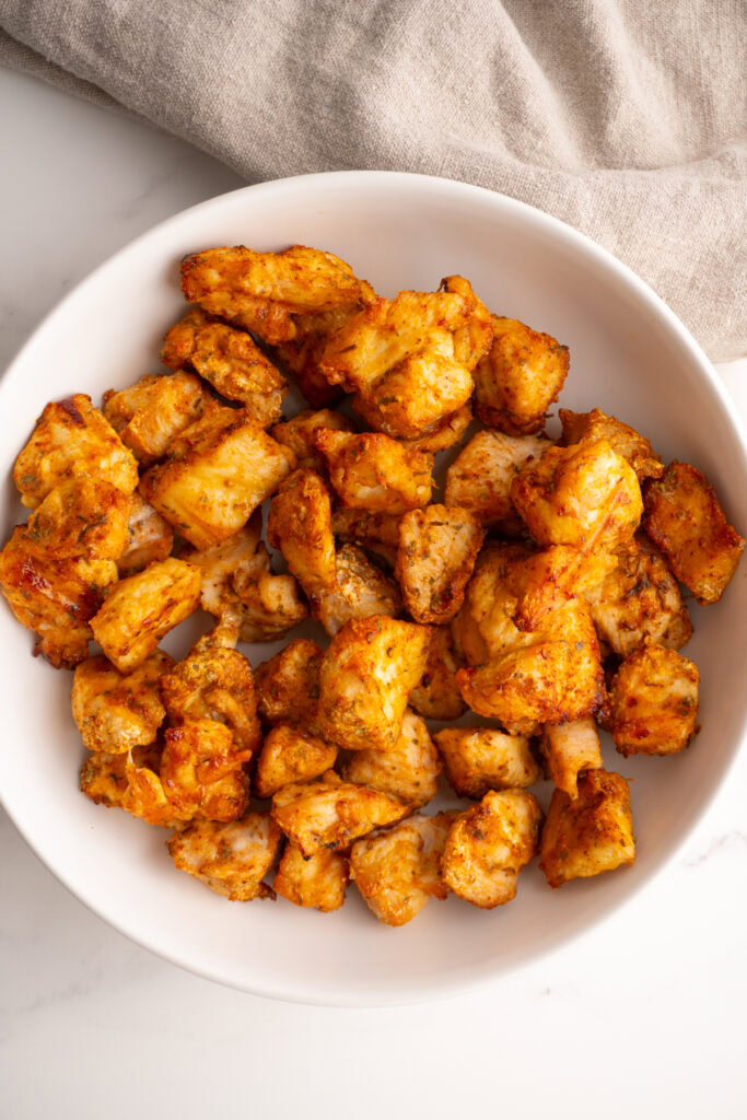 Overhead shot of air fryer chicken bites served in a white bowl.