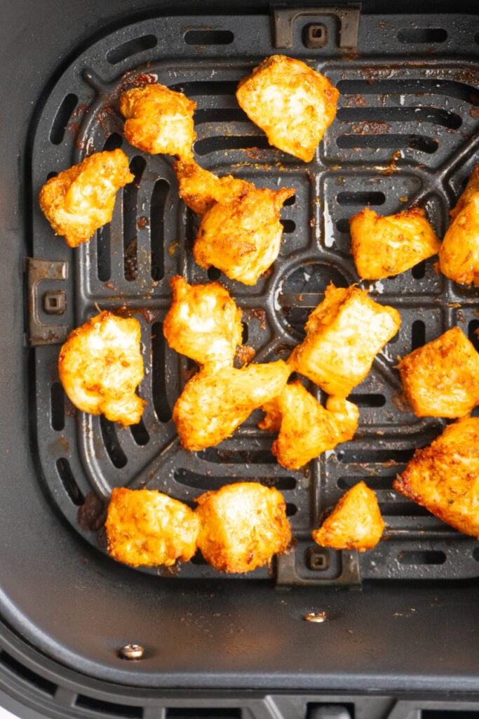 Crispy fried chicken bites cooked in air fryer in the air fryer basket.
