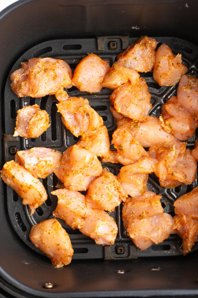 Chicken bites in the air fryer basket before being cooked.