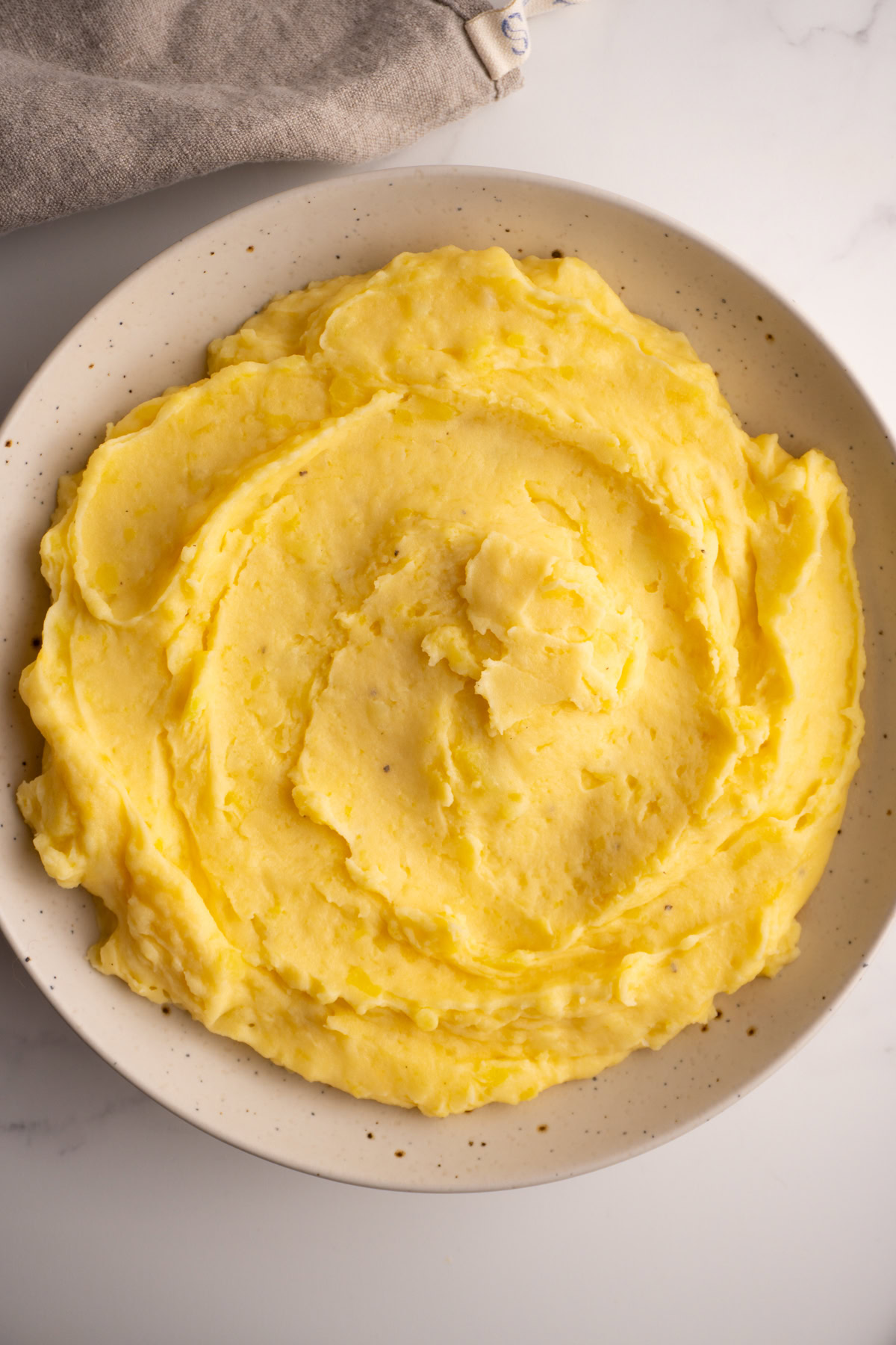 Overhead shot of cheesy mashed potatoes served in a serving bowl.