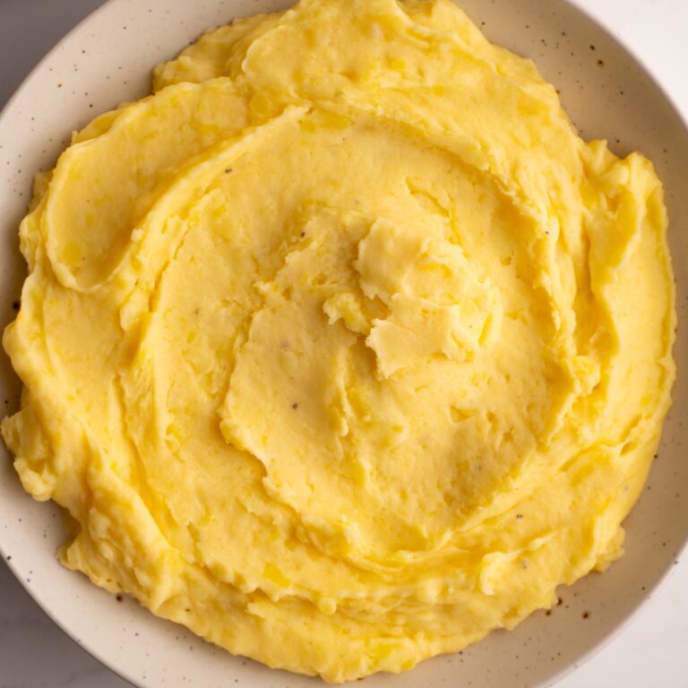 Overhead shot of cheesy mashed potatoes served in a bowl.