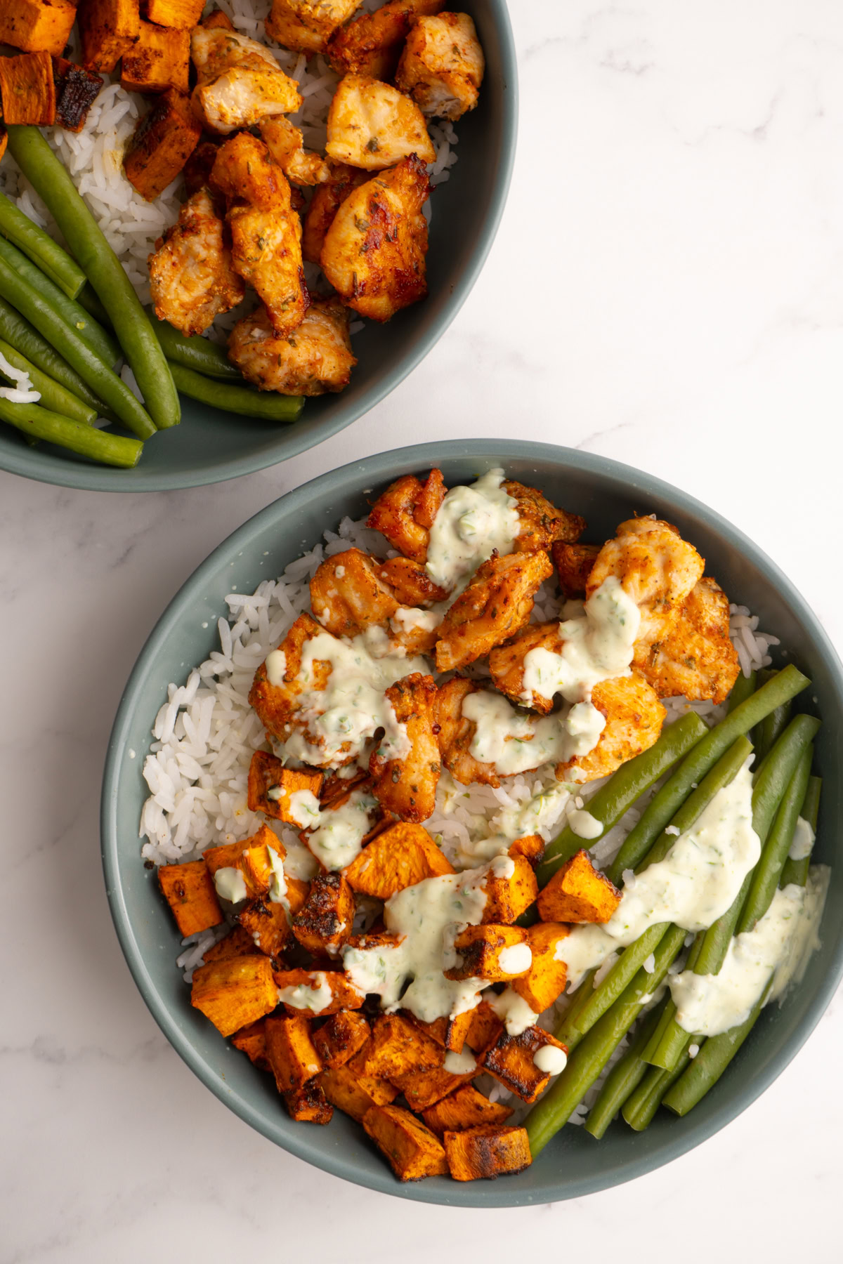 Overhead shot of a chicken sweet potato bowl with a drizzle of sauce on the top.