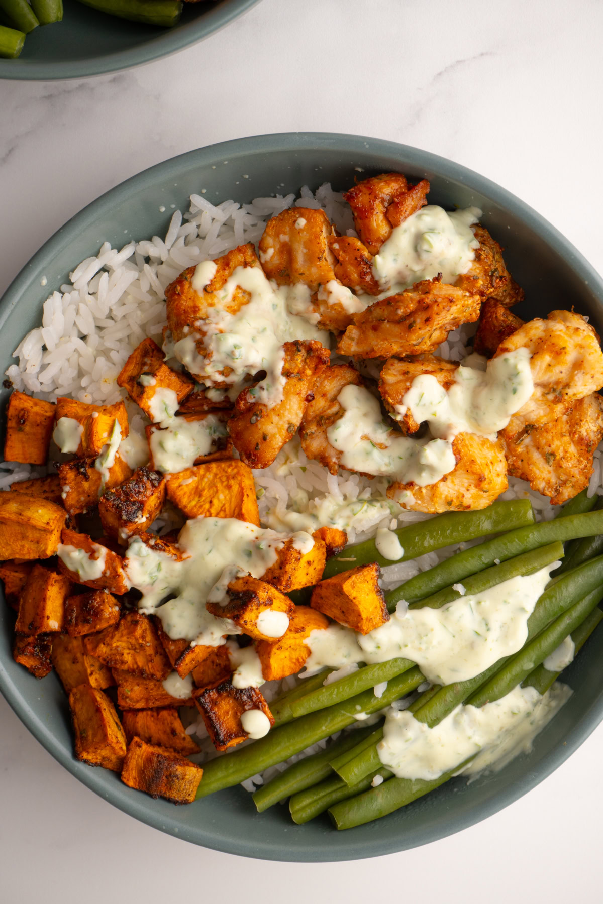 Chicken sweet potato bowls with dressing on top.